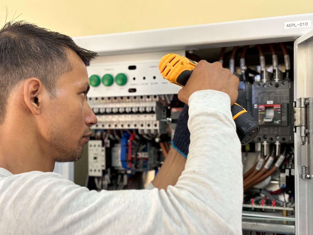 Electrician using a drill on an electrical panel